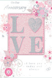In this image, a beautifully composed anniversary card lies gently on a pale surface, its design a soft celebration of enduring romance, much like a pastel bouquet arriving at a doorstep in Farnborough. The focal point is the word LOVE, rendered in raised, soft glitter that gives each letter a velvety shimmer. At the centre of the word, the O has been transformed into a shimmering silver heart, textured and sparkling like a single standout bloom nestled amid more delicate flowers in an arrangement from Flowers Farnborough. The surrounding design unfolds in a halo of blush, mauve, and muted pink blossoms, painted or illustrated with an almost watercolour softness. Their petals and slender stems drift outward in flowing arcs, evoking movement and care, similar to how a florist arranges stems to curve naturally in a hand-tied anniversary bouquet for a home near North Camp. Tiny flourishes-petals in mid-fall, swirling lines, and faintly sketched butterflies-add a sense of whimsy and lightness, calling to mind the grace of an English spring garden after a gentle breeze. The background stays largely soft and uncluttered, allowing the central heart and flowers to glow. Elegant script displays phrases such as On Our Anniversary and I love you today and always, set in a refined, understated style that feels sincere rather than showy. The overall mood is intimate yet quietly festive, perfect for a couple marking another year together in Farnborough, whether they live close to the bustling town centre or in a quieter street by Southwood. It is the kind of card you'd tuck beside fresh roses and seasonal blooms, completing a heartfelt anniversary gesture delivered right to their door.